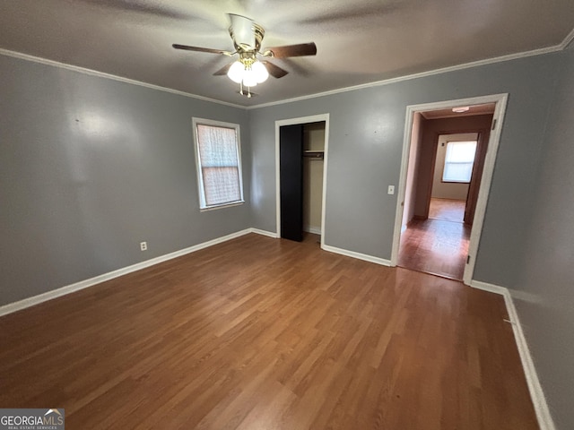 unfurnished bedroom featuring ceiling fan, hardwood / wood-style floors, a closet, and crown molding