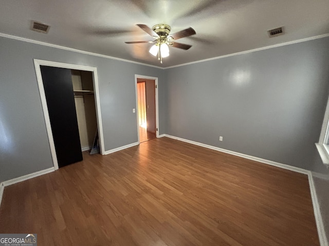 unfurnished bedroom with ceiling fan, a closet, crown molding, and hardwood / wood-style flooring