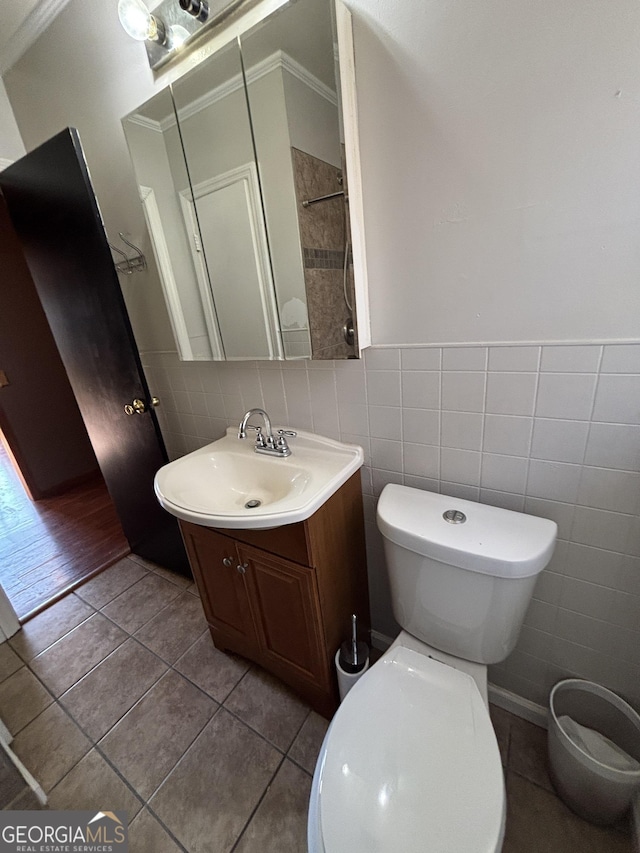 bathroom with toilet, vanity, tile patterned flooring, tile walls, and crown molding