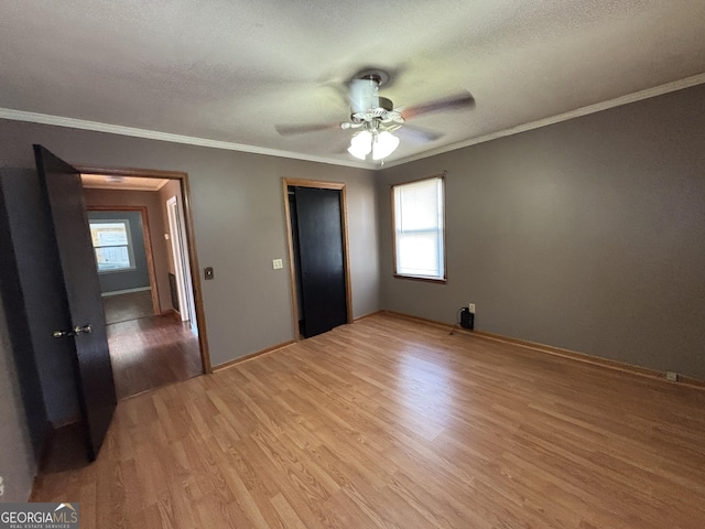 unfurnished bedroom with light wood-type flooring, ceiling fan, crown molding, and multiple windows