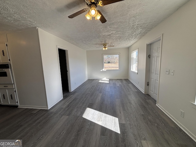 unfurnished living room featuring ceiling fan, a textured ceiling, and dark hardwood / wood-style floors