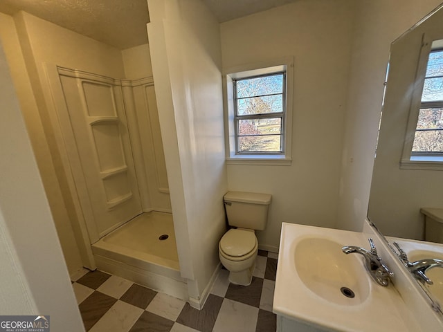 bathroom featuring a shower, plenty of natural light, toilet, and vanity