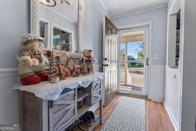 doorway to outside featuring a textured ceiling, crown molding, and hardwood / wood-style flooring