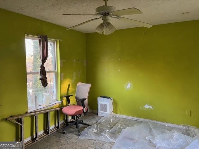 living area with ceiling fan and a textured ceiling