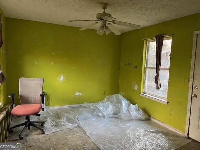 interior space with ceiling fan and a textured ceiling