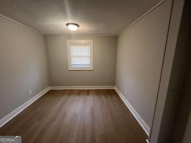 unfurnished room featuring dark hardwood / wood-style flooring and a textured ceiling