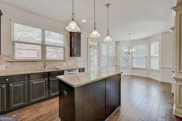 kitchen featuring decorative light fixtures, sink, dark brown cabinetry, and a center island