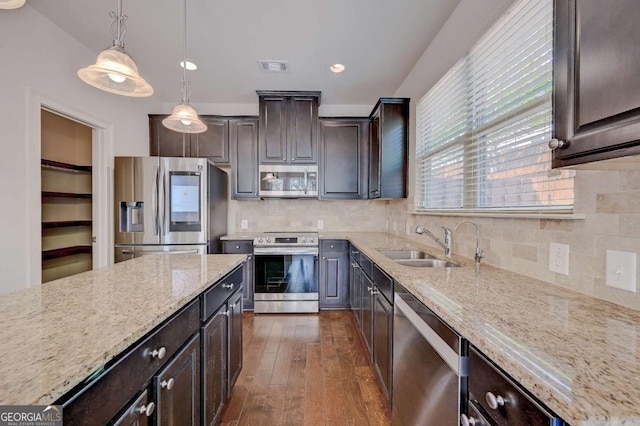 kitchen featuring appliances with stainless steel finishes, pendant lighting, backsplash, and dark brown cabinetry