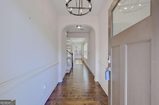 corridor featuring dark wood-type flooring and a chandelier