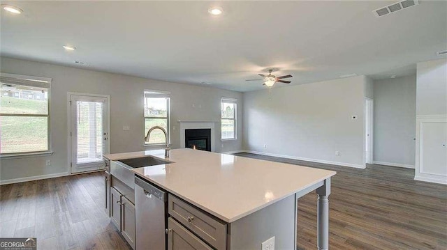 kitchen featuring ceiling fan, dishwasher, a center island with sink, and sink