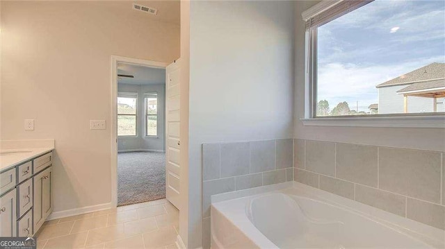 bathroom with tile patterned flooring, a bathtub, and vanity