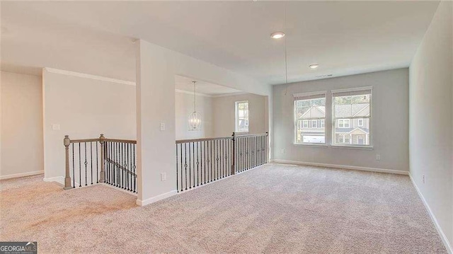 carpeted empty room featuring a notable chandelier