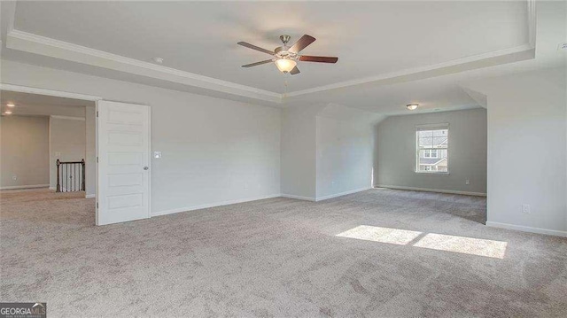 spare room featuring ceiling fan, light colored carpet, and a tray ceiling