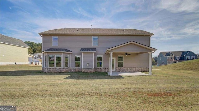 rear view of house with ceiling fan, a patio area, and a lawn