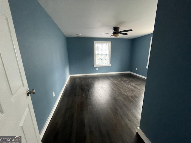 empty room with ceiling fan and dark hardwood / wood-style flooring