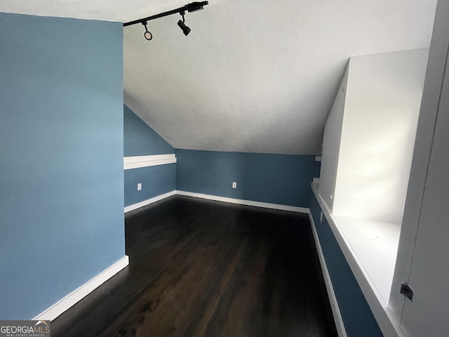 additional living space featuring a textured ceiling, lofted ceiling, and hardwood / wood-style flooring