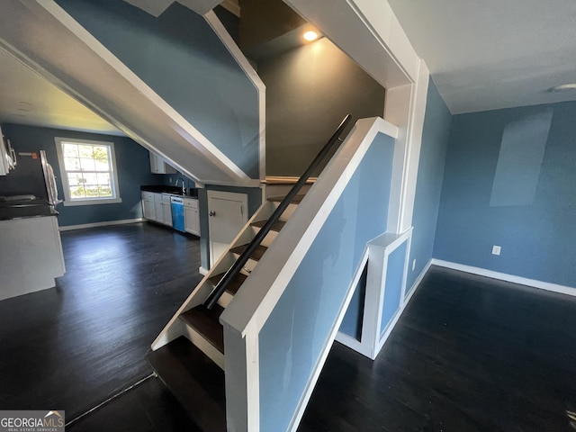 staircase featuring vaulted ceiling, hardwood / wood-style floors, and sink