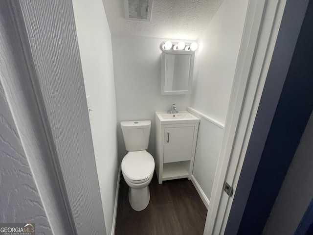 bathroom featuring toilet, vanity, a textured ceiling, and hardwood / wood-style flooring