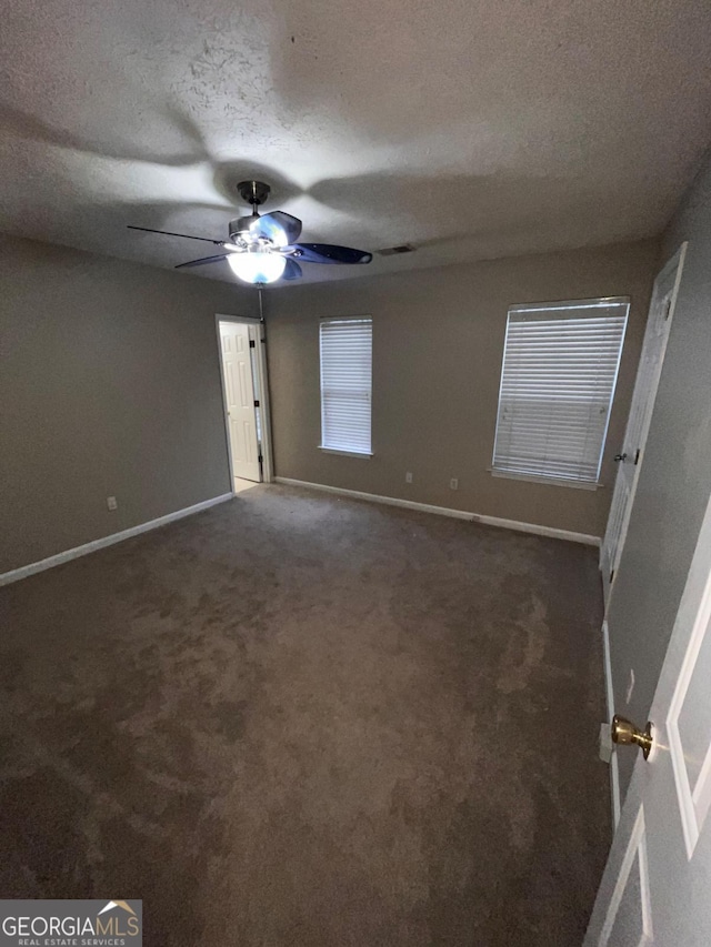 unfurnished room with dark colored carpet, ceiling fan, and a textured ceiling