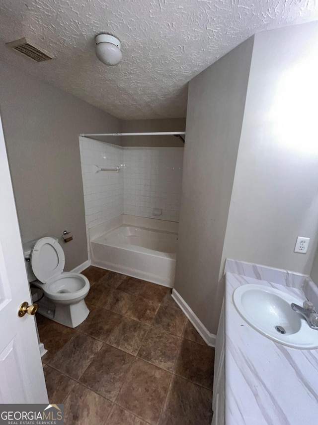 full bathroom with tiled shower / bath, vanity, a textured ceiling, and toilet