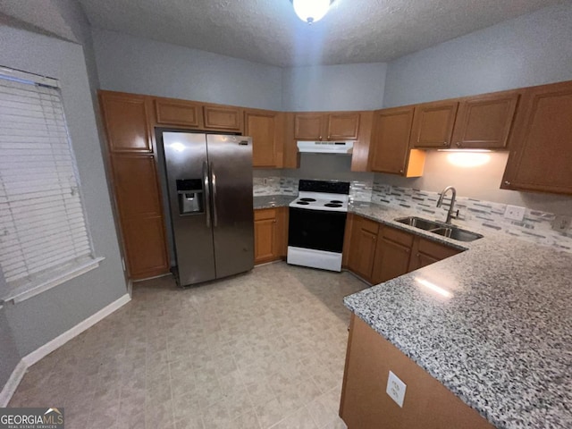 kitchen with sink, electric range, stainless steel refrigerator with ice dispenser, light stone counters, and a textured ceiling