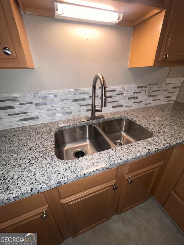 kitchen featuring tasteful backsplash, light stone countertops, and sink