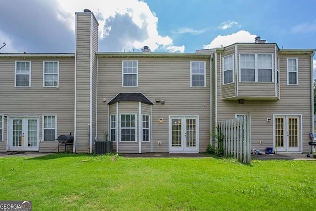 rear view of house with central AC unit, a yard, and french doors