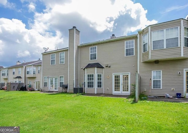 rear view of house featuring french doors, central AC unit, and a lawn