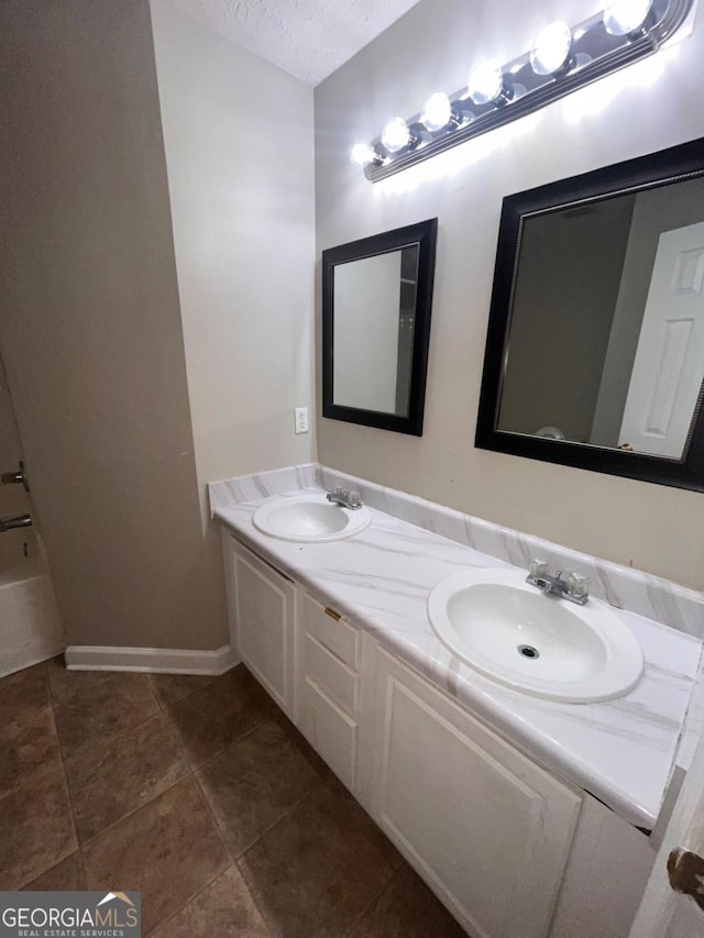 bathroom with vanity, a bathing tub, tile patterned floors, and a textured ceiling