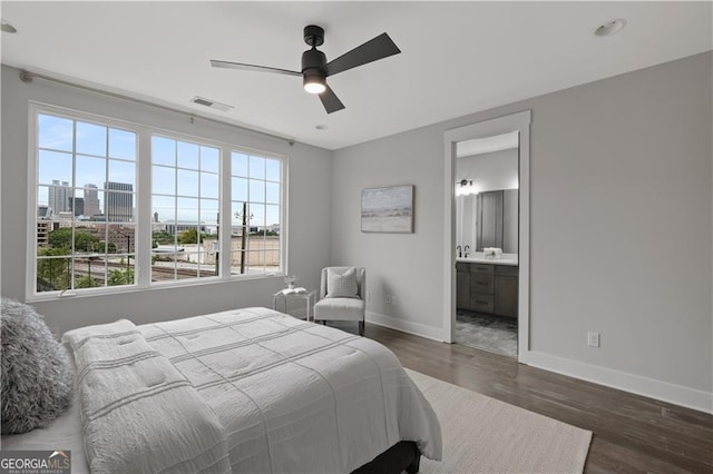 bedroom with ceiling fan, dark wood-type flooring, and connected bathroom