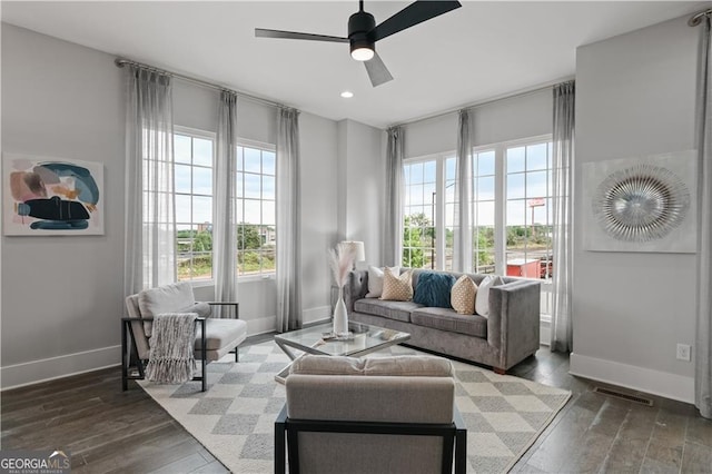 living area with ceiling fan, plenty of natural light, and dark hardwood / wood-style flooring