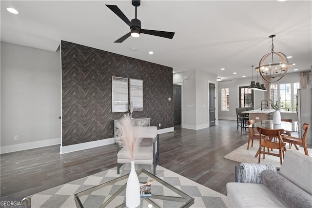 living room featuring dark hardwood / wood-style floors, sink, and ceiling fan with notable chandelier