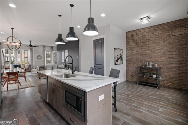 kitchen with an island with sink, appliances with stainless steel finishes, a notable chandelier, decorative light fixtures, and sink