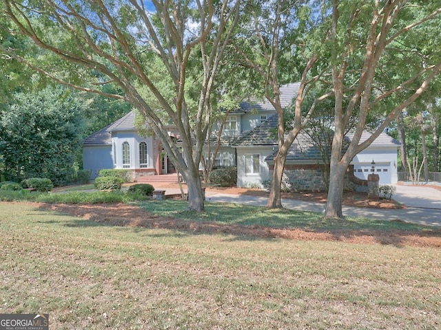 obstructed view of property with a front lawn and a garage