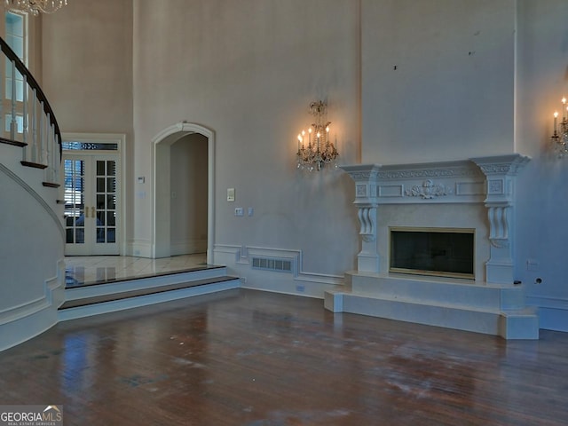 unfurnished living room featuring an inviting chandelier, a fireplace, and a towering ceiling