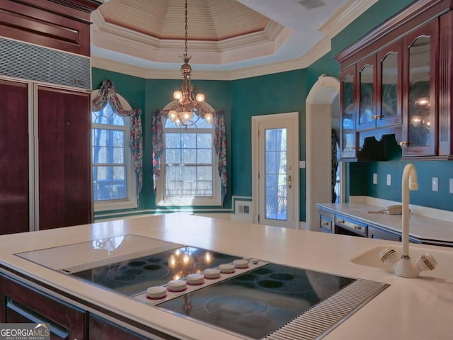 kitchen featuring an inviting chandelier, black electric stovetop, a raised ceiling, decorative light fixtures, and crown molding