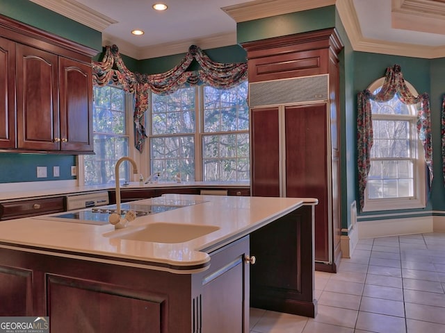 kitchen featuring a center island with sink, sink, crown molding, light tile patterned floors, and paneled built in refrigerator