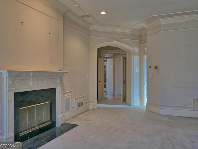 unfurnished living room with a high end fireplace, crown molding, and carpet