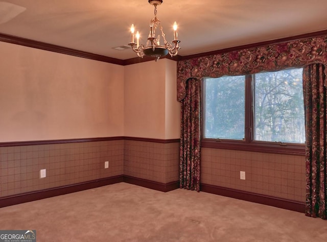 carpeted spare room with a healthy amount of sunlight, a chandelier, and crown molding