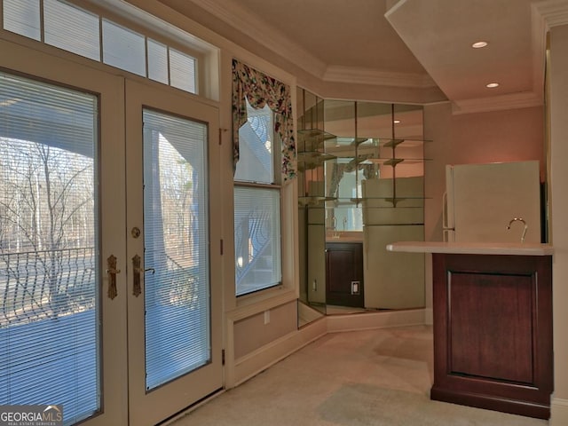 entryway with light carpet, ornamental molding, and french doors