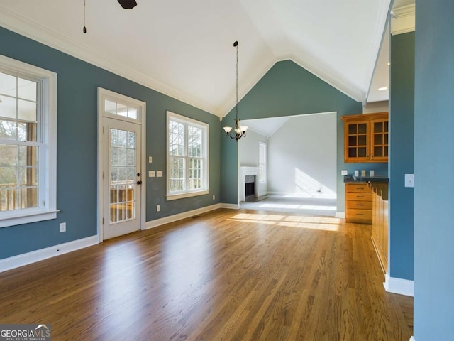 unfurnished living room with lofted ceiling, dark hardwood / wood-style flooring, ceiling fan with notable chandelier, and crown molding