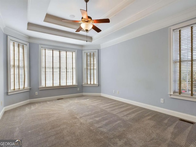 carpeted empty room with ceiling fan, ornamental molding, and a raised ceiling