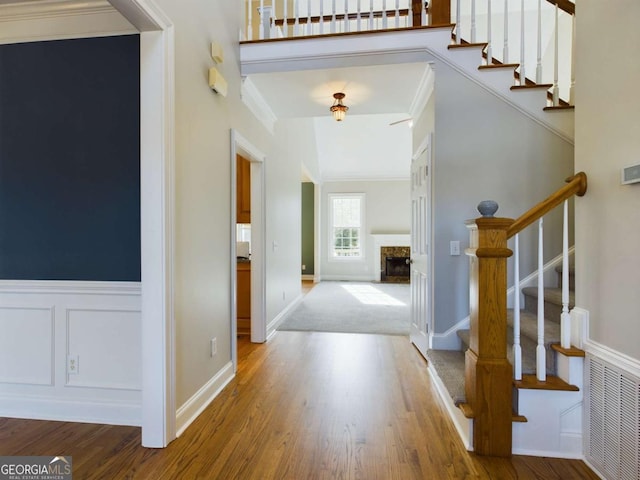 entrance foyer featuring hardwood / wood-style flooring, crown molding, and a fireplace