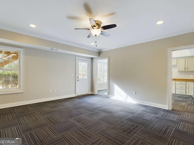 spare room with ceiling fan, dark carpet, and crown molding