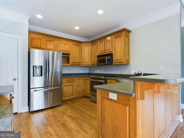 kitchen with stainless steel appliances, sink, kitchen peninsula, hardwood / wood-style flooring, and crown molding