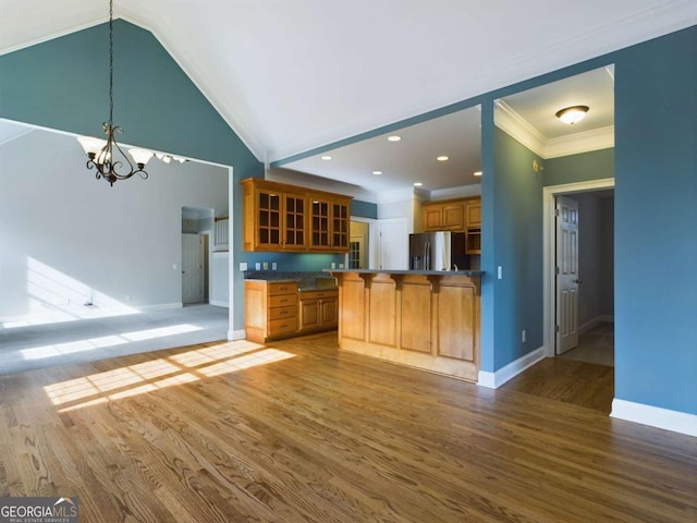 kitchen featuring stainless steel fridge with ice dispenser, a chandelier, vaulted ceiling, light hardwood / wood-style flooring, and crown molding