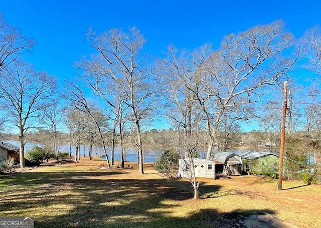 view of yard featuring a water view and a shed