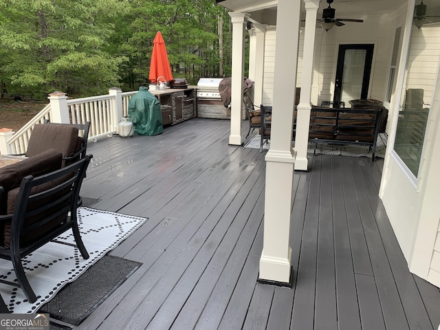 wooden terrace with grilling area, ceiling fan, and an outdoor kitchen