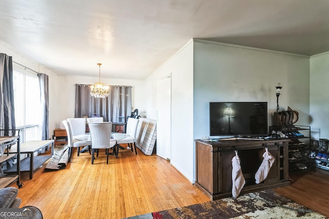 dining space with light wood-type flooring, crown molding, and a notable chandelier