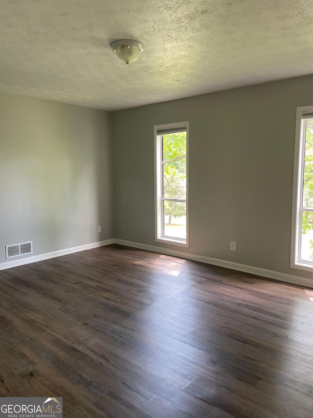 spare room with a textured ceiling and dark hardwood / wood-style floors